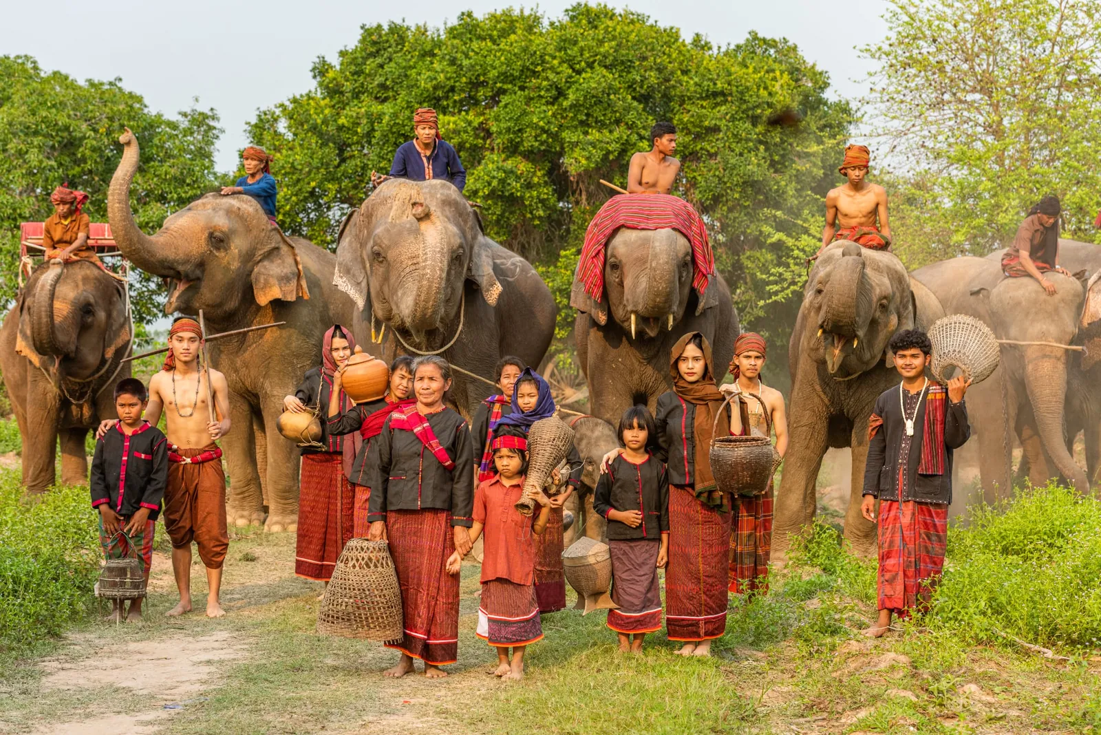 ชาวกูยหลายรุ่นในชุดพื้นถิ่น ยืนเรียงกับช้างในหมู่บ้าน